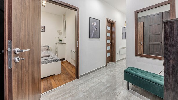 Un pasillo con una puerta de madera, un banco y un espejo enmarcado.