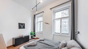 Un dormitorio moderno con una cama grande, un escritorio pequeño y una ventana con cortinas.