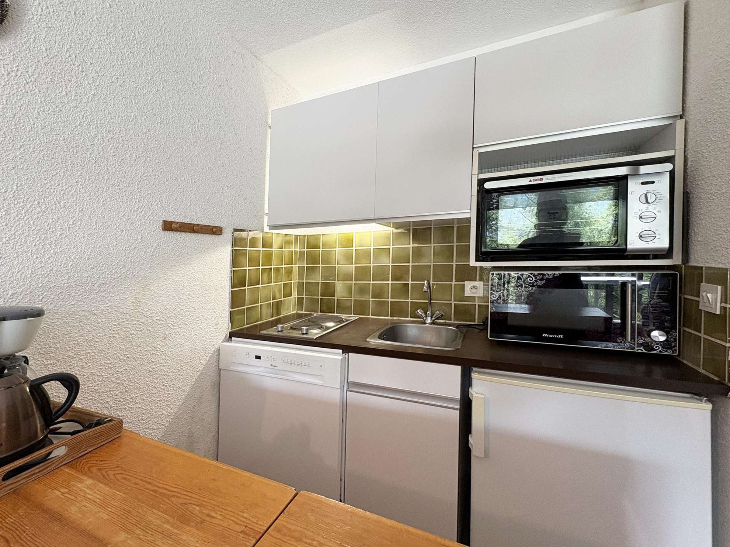 A compact kitchenette with a microwave, toaster, and dishwasher.
