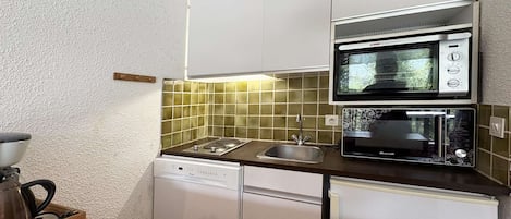 A compact kitchenette with a microwave, toaster, and dishwasher.