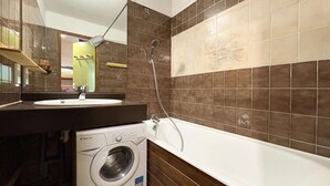 A bathroom with a washing machine, a sink, and a bathtub.