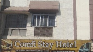 Um edifício de vários andares com uma placa indicando 'Comfi Stay Hotel' no nível térreo.