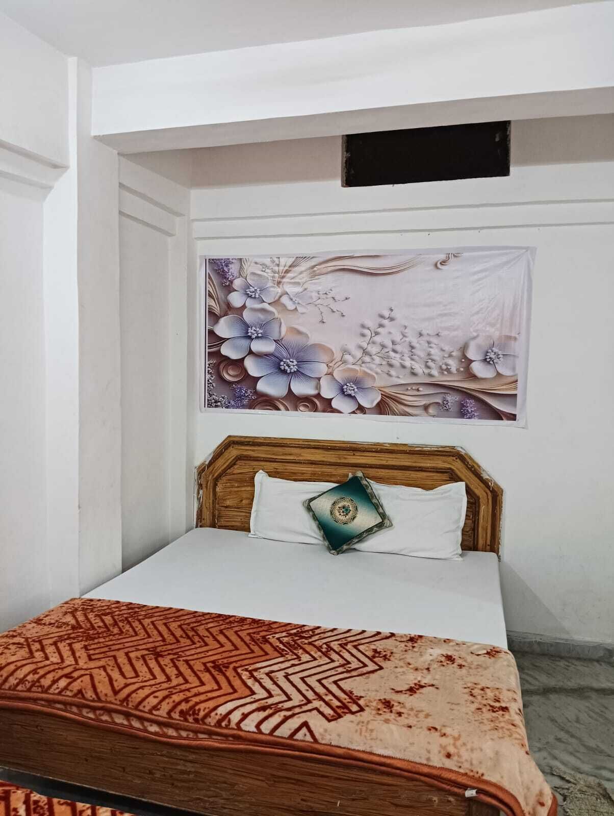 A bedroom with a bed, a decorative wall piece, and a patterned throw blanket.