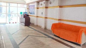 Uma área de recepção com balcão, um sofá e uma grande janela com vista para o exterior.