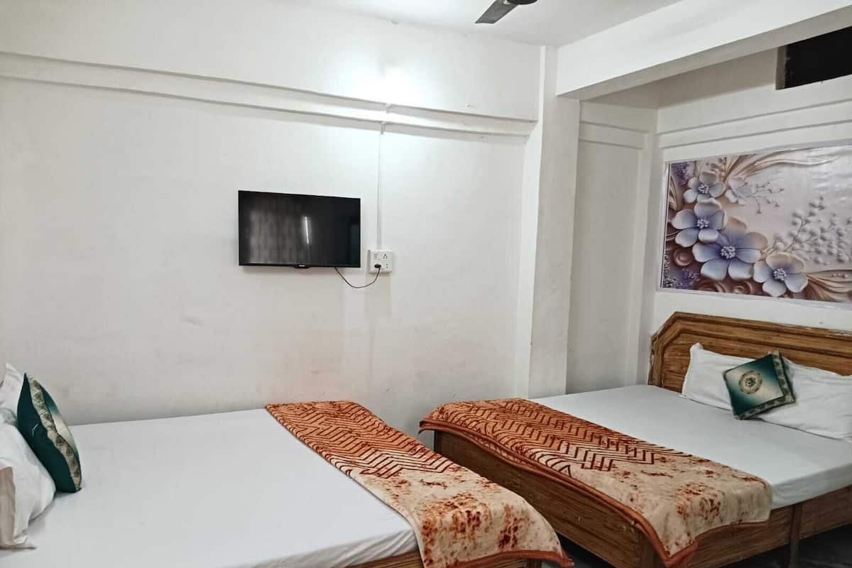 Ein Zimmer mit zwei Holzbett, einem flachbildfernseher an der Wand und einer Wanddekoration mit Blumenmuster.