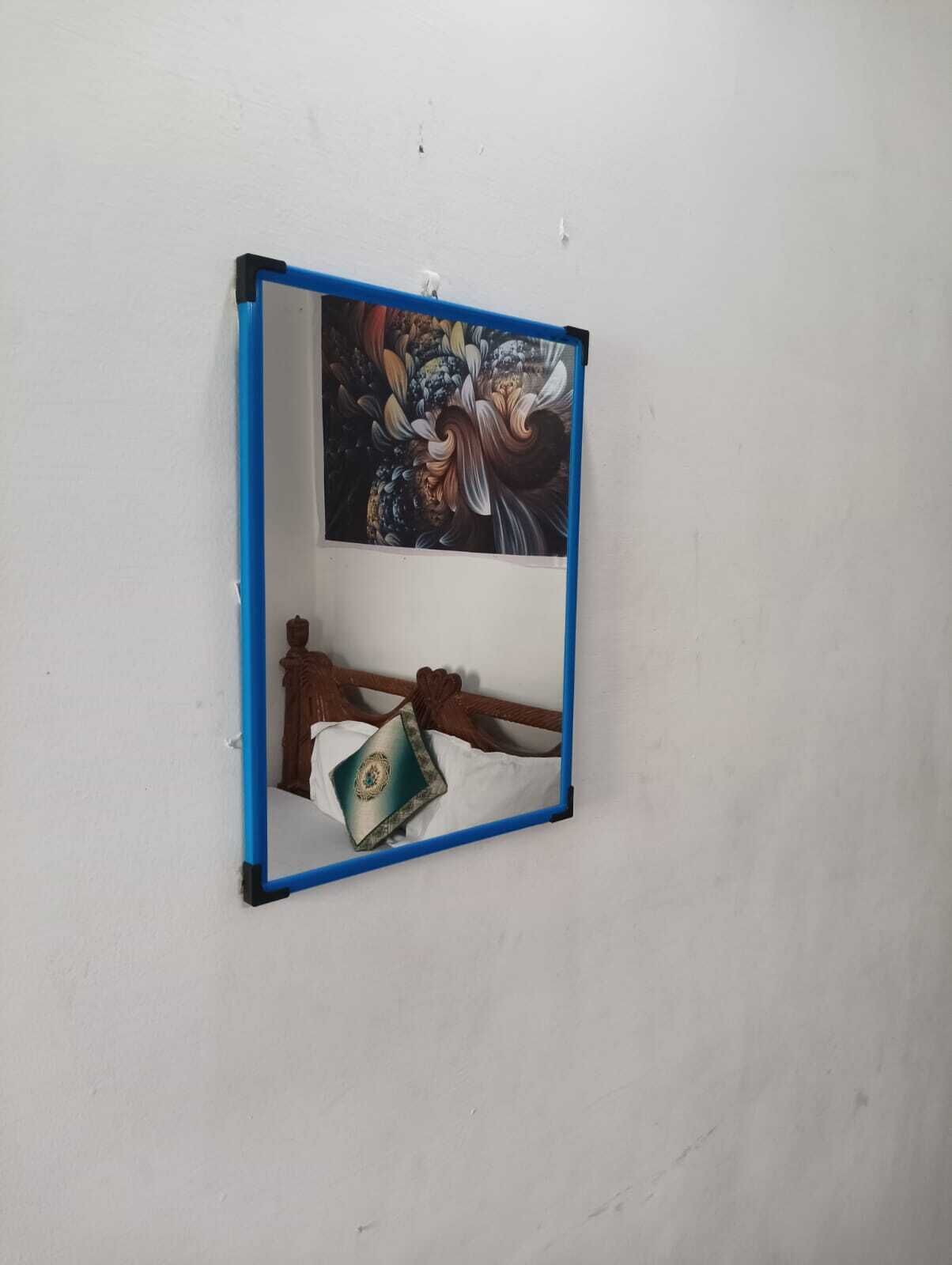 A mirror with a blue frame on a plain wall.