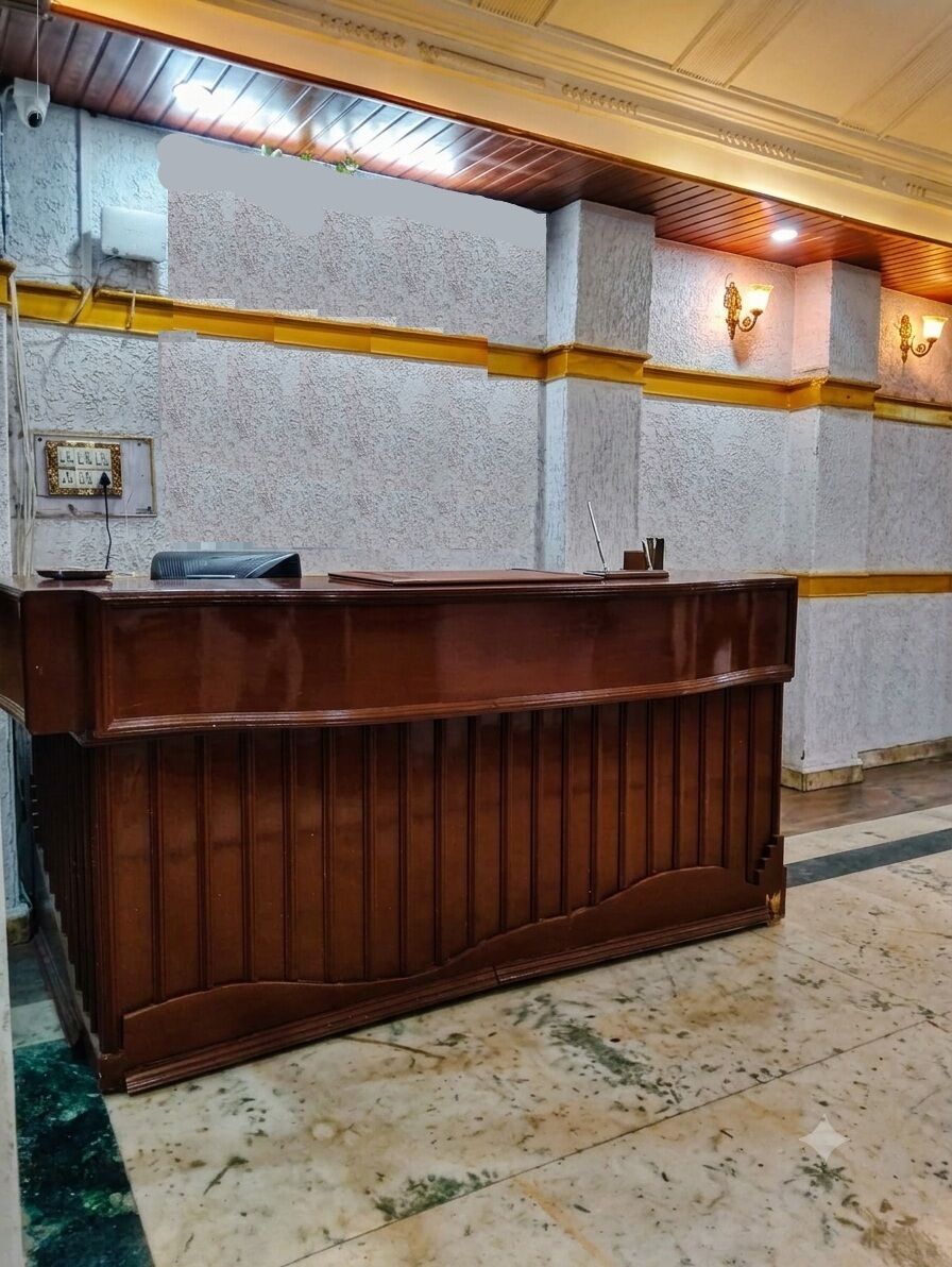 Ein Empfangsschalter mit Holzoptik, vor einer Wand mit Struktur und gelber Linie.