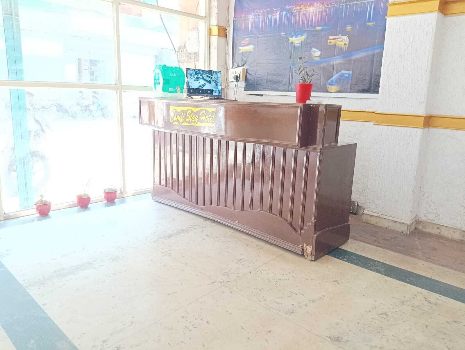 Tauleller de recepció amb pantalla digital, plantes en testos i vista del port a través de grans finestres.