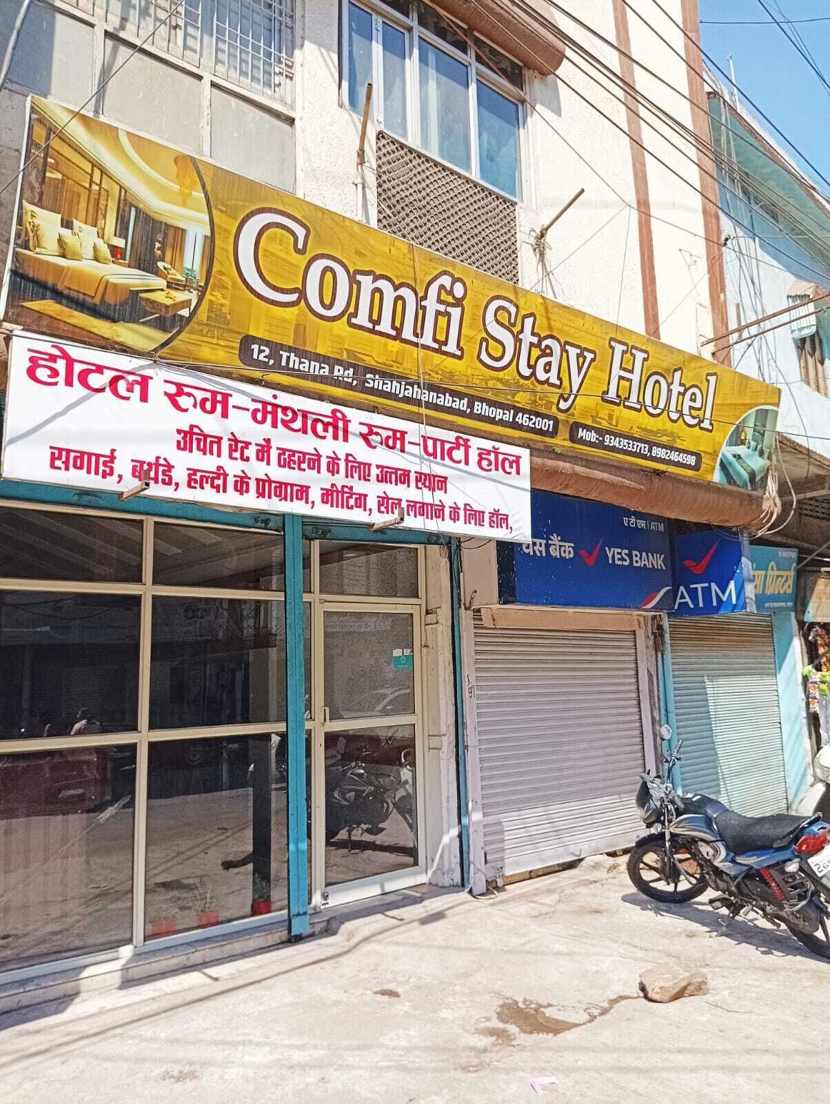 A hotel named Comfi Stay Hotel with a signboard advertising room rates and amenities.