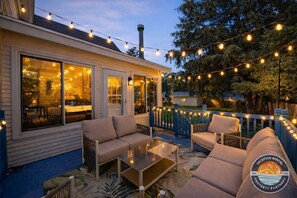 Eine Terrasse im Freien mit Lichterketten, einer Couch und einem Glastisch.