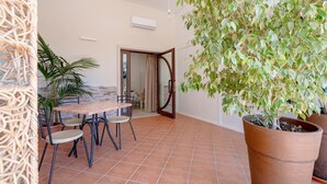A dining area with a table and chairs, a potted plant, and a door leading to another room. - Apartment 'L'Aia - 1' with Shared Pool, Wi-Fi and Air Conditioning (Monopoli)