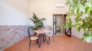 A patio with a table and chairs, a potted plant, and a view of the interior. - Apartment 'L'Aia - 1' with Shared Pool, Wi-Fi and Air Conditioning (Monopoli)