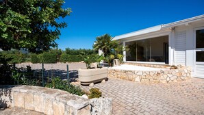 A house with a paved patio, stone walls, and a large window. - Apartment 'L'Aia - 2' with Shared Pool, Wi-Fi and Air Conditioning (Monopoli)