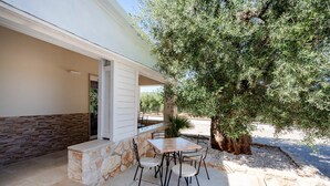 An outdoor patio with stone walls, a table, and chairs. - Apartment 'L'Aia - 4' with Shared Pool, Wi-Fi and Air Conditioning (Monopoli)