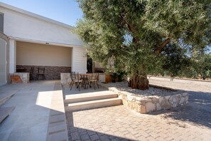 A covered outdoor area with a stone bench, a table, and chairs.