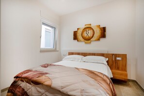 A bedroom with a bed, a window, and a wall-mounted artwork.