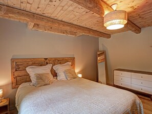 Une chambre à coucher avec une tête de lit en bois, un grand lit avec une literie blanche, une lampe de chevet, une commode et un miroir.