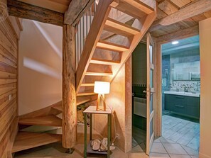 Un escalier en bois mène à une salle de bain dotée d’un lavabo moderne et de murs carrelés.