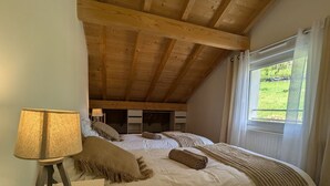 Ein Schlafzimmer mit Holzboden, einem großen Bett mit weißer Bettwäsche, einer Lampe und Blick auf Grünflächen.