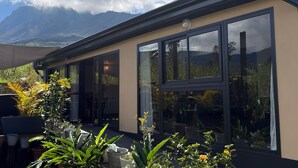 A modern building with large windows, a flat roof, and a mountain backdrop. - Spacious villa in Grand Coude with wheelchair access (Saint-Joseph)