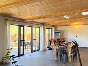 A spacious room with a wooden ceiling, a dining table with chairs, and a sliding glass door leading to an outdoor area. - Spacious villa in Grand Coude with wheelchair access (Saint-Joseph)