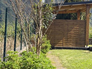 A garden with a wooden pergola, a metal fence, and a variety of plants. - Spacious villa in Grand Coude with wheelchair access (Saint-Joseph)