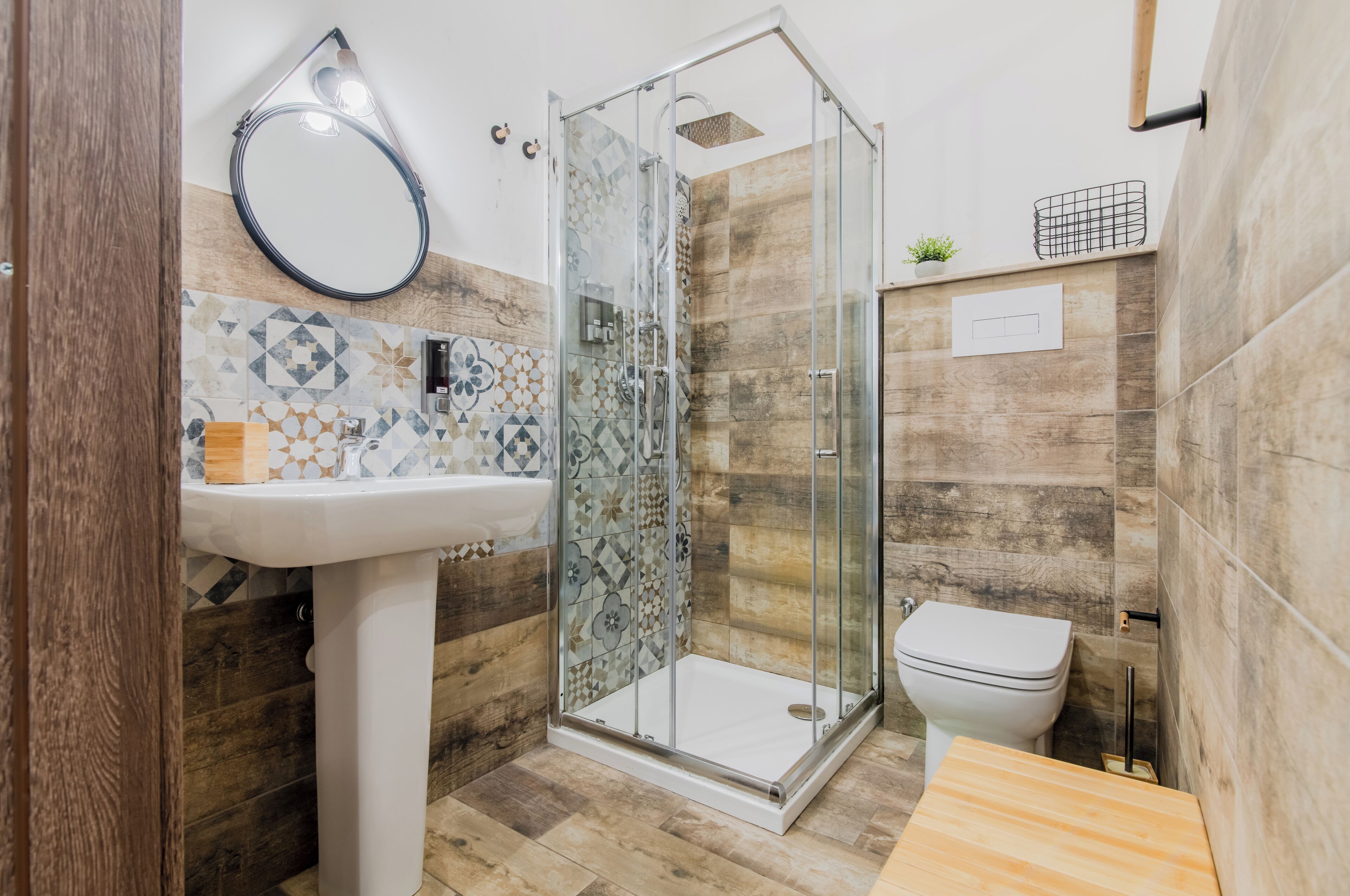 Un baño moderno con cabina de ducha de vidrio, lavamanos pedestal y retrete.