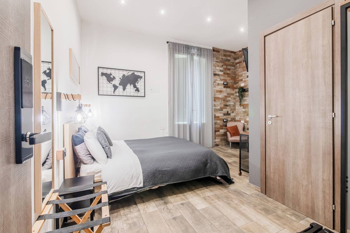 Un dormitorio moderno con cama, armario, escritorio con silla y un ventanal con cortinas.