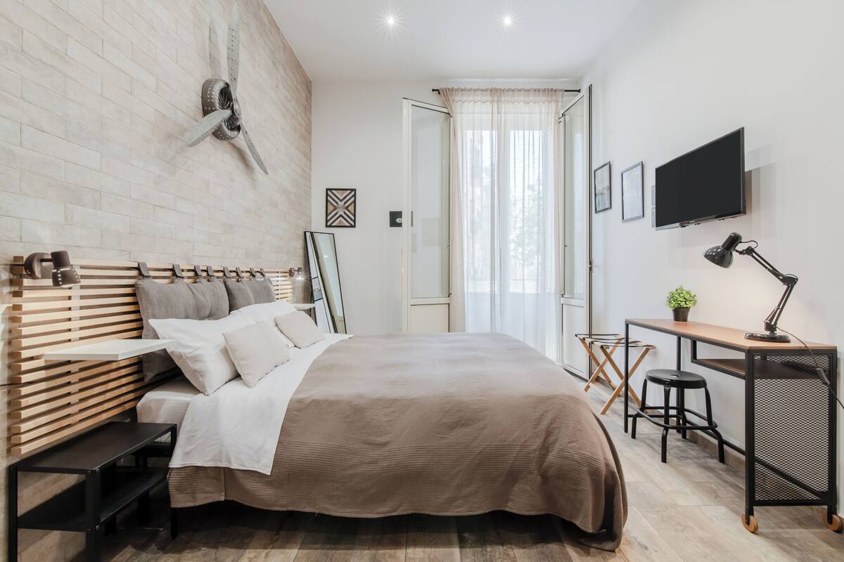 Un dormitorio moderno con una cama grande, un escritorio y un televisor.