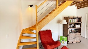 A wooden staircase with a red chair and ottoman in a room with a bookshelf and a sign.