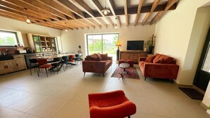 A spacious living area with a kitchen, dining area, and seating with a TV and plants.