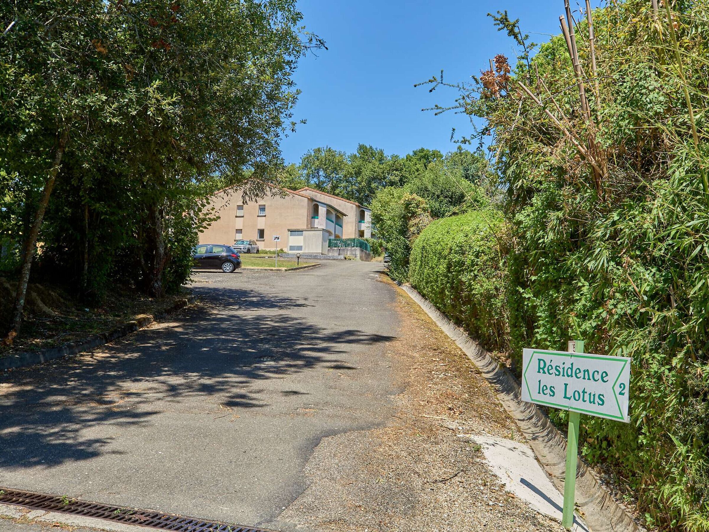 A road leading to a building with a sign reading "Résidence les Lotus".