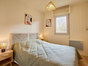 Quarto com cama, abajures, janela com vista e obras de arte nas paredes.