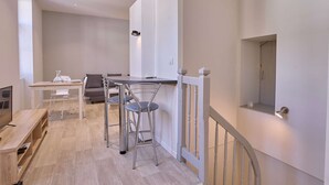 A modern apartment with a dining area, a sofa, a TV, and a kitchen area. - Charming renovated T2 in Barbotan, pets allowed, free parking and Wifi (Barbotan-les-Thermes)