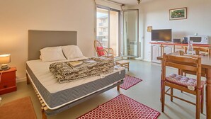 Une chambre à coucher avec un lit, un bureau avec une télévision et une chaise.