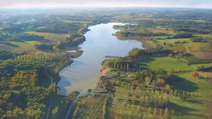 Vue aérienne d’une rivière serpentant à travers un paysage rural, avec des champs et des arbres.