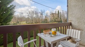 A balcony with a table and two chairs, a pitcher, and a basket. - Charming T2 apartment for 2 people, pets allowed (Barbotan-les-Thermes)