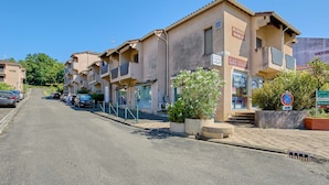 Une rangée d’immeubles résidentiels dotés de balcons, une enseigne bien visible indiquant la présence d’une laverie, et un ciel dégagé.