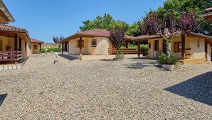 A row of rustic, single-story buildings with tiled roofs, surrounded by gravel and trees. - T2 Apartment with Terrace - Pets Allowed in Barbotan-les-Thermes (Barbotan-les-Thermes)