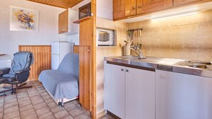 A compact kitchen with wooden cabinets, a microwave, and a sink. - Apartment T2 with porch and pets allowed (Barbotan-les-Thermes)