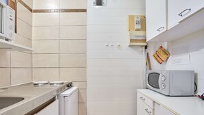 A compact kitchen with a microwave, a sink, and a small trash bin. - South-Facing Studio with Balcony, WIFI and Pets Allowed - For 2 People (Barbotan-les-Thermes)
