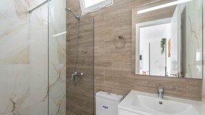 A modern bathroom with a glass shower enclosure, a white sink, and a wooden wall panel.