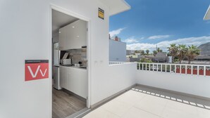 A balcony with a white railing, a kitchen area with white cabinets, and a sign indicating a vacation rental.