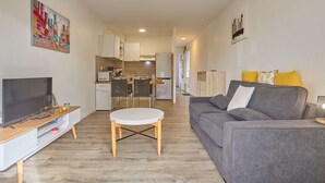 A compact living space with a sofa, a TV, a dining table, and a kitchen area. - Spacious renovated T2 with balcony, wifi and pets allowed in Barbotan-les-Thermes (Barbotan-les-Thermes)