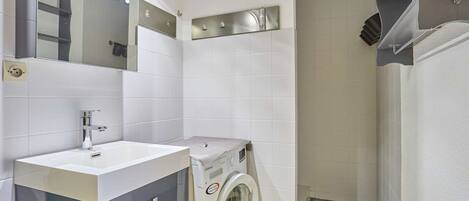 A modern bathroom with a sink, mirror, and a built-in washing machine.