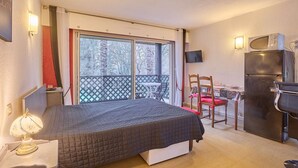 Un dormitorio con una cama, un escritorio, una silla, un televisor y un refrigerador.