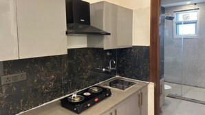 Una cocina con estufa a gas, salpicadero de mármol negro y armarios blancos.