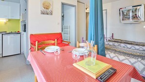 Un espace de vie compact comprenant un coin repas, une kitchenette et un lit avec une literie à motifs.