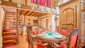 A dining area with a round table, red upholstered chairs, and a wooden cabinet with ornate carvings. - T3 House with fireplace for 4 people, pets allowed in Cazaubon (Cazaubon)