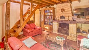A cozy living room with a fireplace, a bookshelf, a red sofa, and a wooden staircase. - T3 House with fireplace for 4 people, pets allowed in Cazaubon (Cazaubon)